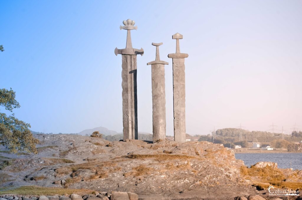 Trois épées vikings monumentales en granit érigées face à un fjord, symbole de paix et d'unité