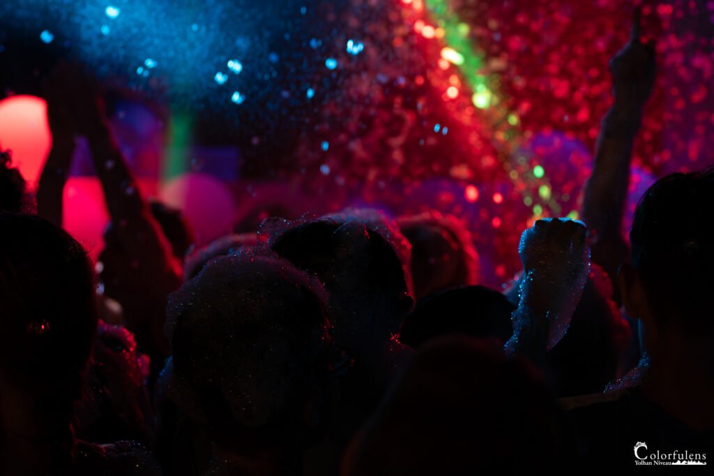 Une nuée de lumières colorées, capturant l'atmosphère électrique et le joyeux chaos d'une soirée festive où la musique et les paillettes s'entremêlent en une danse vibrante.