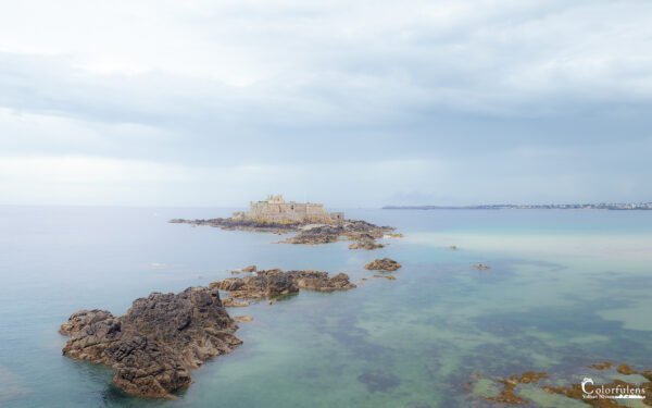Le Fort National de Saint-Malo émerge entouré par les eaux claires et les rochers, révélant un paysage breton captivant et historique.