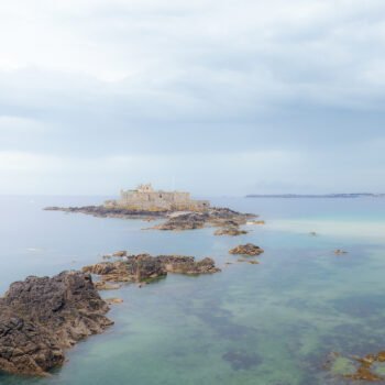 Le Fort National de Saint-Malo émerge entouré par les eaux claires et les rochers, révélant un paysage breton captivant et historique.