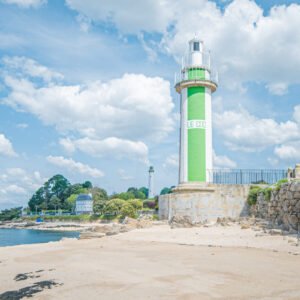 Phare de Benodet en Bretagne sur fond de ciel bleu, représentant la tranquillité de la côte avec son phare vert et blanc emblématique.