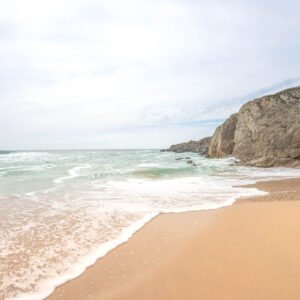 Plage sauvage de Quiberon sous un ciel nuageux en Bretagne, montrant des nuages épars avec des falaises imposantes sur le rivage.
