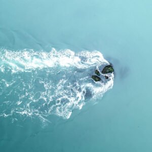 Deux rochers isolés balayés par des vagues turquoise sur la côte de Morbihan.