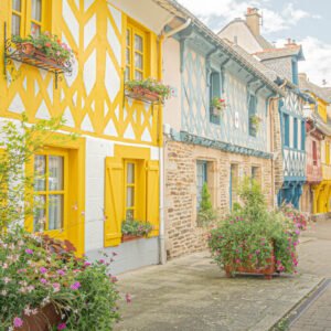Rue pittoresque à Josselin, Bretagne, mettant en valeur des maisons colorées et des fleurs abondantes, symbole de l'hospitalité bretonne.
