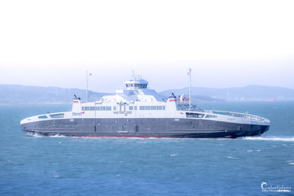 Ferry Mastrafjord traversant les eaux paisibles d'un fjord de Norvège sous un ciel dégagé, alliant technologie et nature.