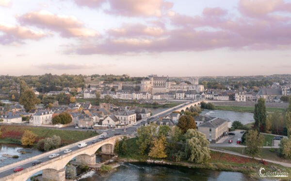 Vue aérienne d'Amboise au coucher de soleil, avec le Château d'Amboise surplombant la Loire et le pont en arche, unissant histoire et nature.