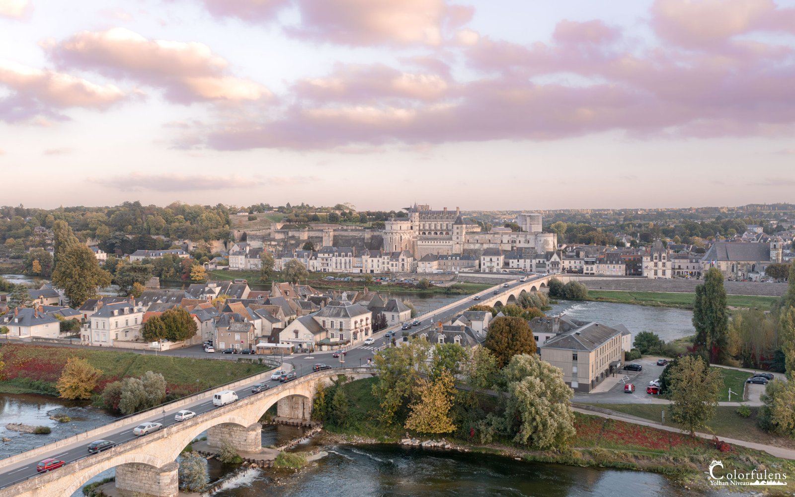 Vue aérienne d'Amboise au coucher de soleil, avec le Château d'Amboise surplombant la Loire et le pont en arche, unissant histoire et nature.