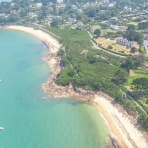 Vue aérienne de Carantec : Découvrez le charme pittoresque d'un village côtier breton avec ses plages dorées et ses eaux turquoises sous un ciel dégagé.