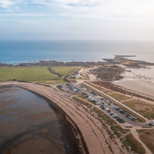 Vue aérienne saisissante de la plage de Penvins, illustration de la beauté tranquille de la côte bretonne, avec chapelle isolée et routes côtières invitant à l'évasion.