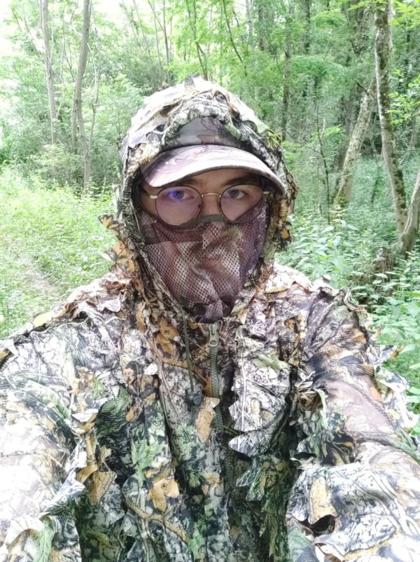 Chasseur en tenue camouflage dans la forêt dense, illustrant la stratégie de se fondre dans la nature pour observer la faune en silence.