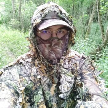 Chasseur en tenue camouflage dans la forêt dense, illustrant la stratégie de se fondre dans la nature pour observer la faune en silence.